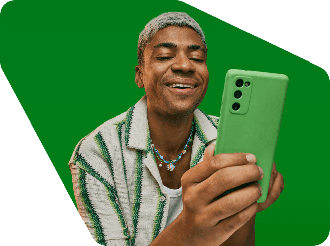Empreendedor em um fundo verde sorrindo e olhando para o seu celular com uma capinha verde. 