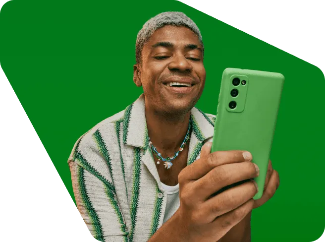 Empreendedor em um fundo verde sorrindo e olhando para o seu celular com uma capinha verde.