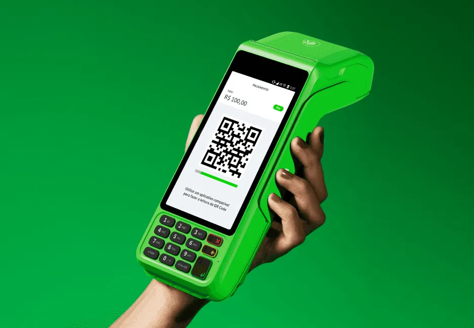 Em um fundo verde, uma mão de mulher segurando uma máquina de cartão do Ton com o valor de R$100 no visor, além do QR Code. 